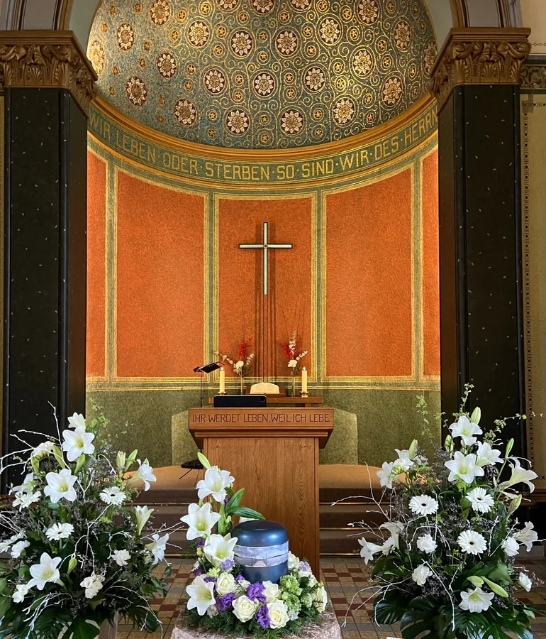 Feierlich gestaltete Kapelle mit Urne, Lilien und Kerzen