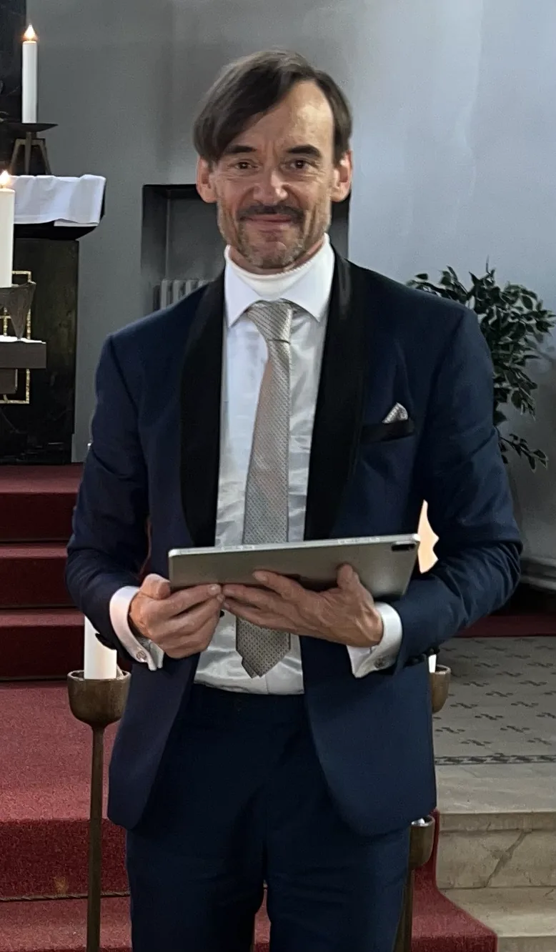 Ron Dietze als Trauerredner in einer Kirche, mit Tablet in der Hand