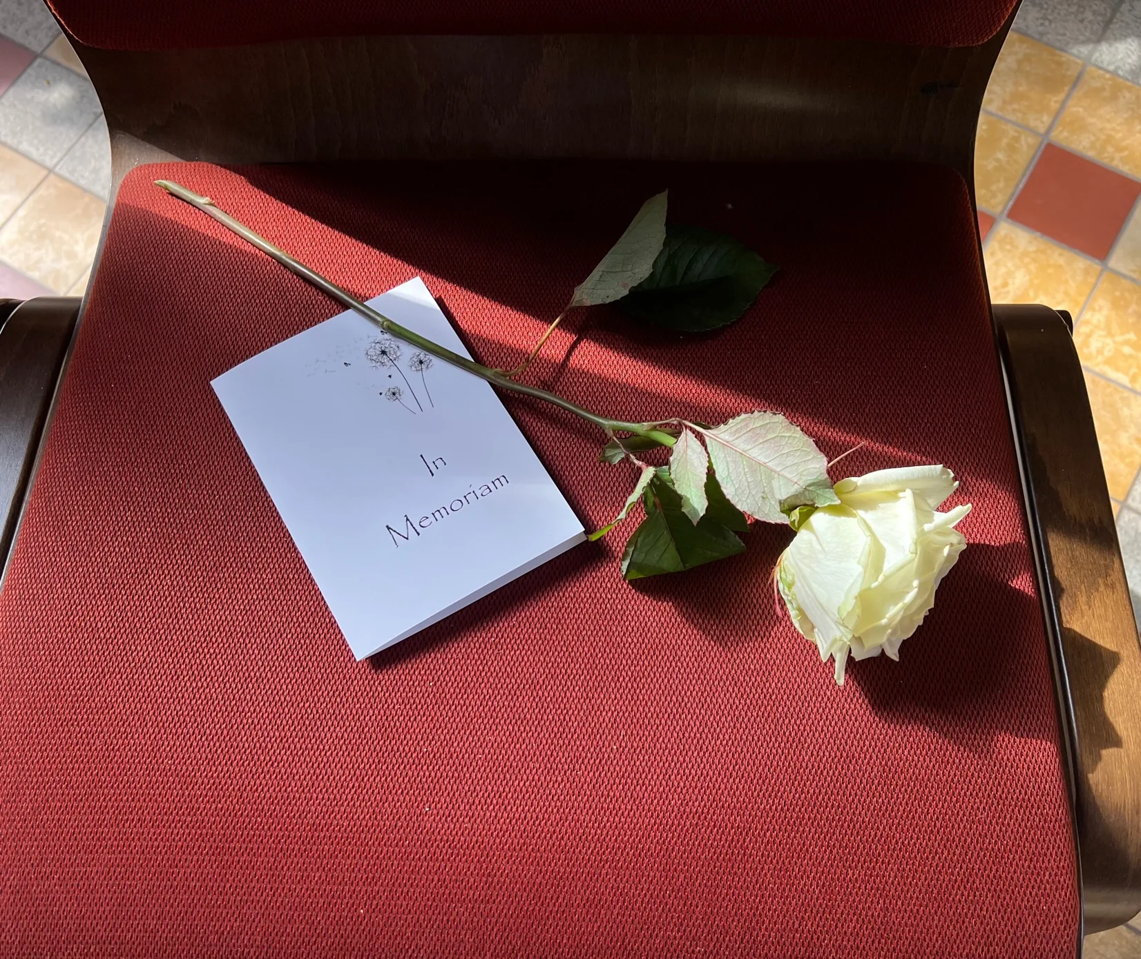 Eine weiße Rose mit einer Trauerkarte auf rotem Samt